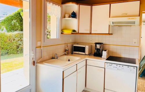 une cuisine avec un évier et un micro-ondes dans l'établissement Maison bord de mer la Turballe, à La Turballe