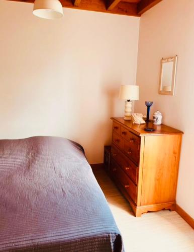 une chambre avec un lit et une lampe sur une commode dans l'établissement Maison bord de mer la Turballe, à La Turballe