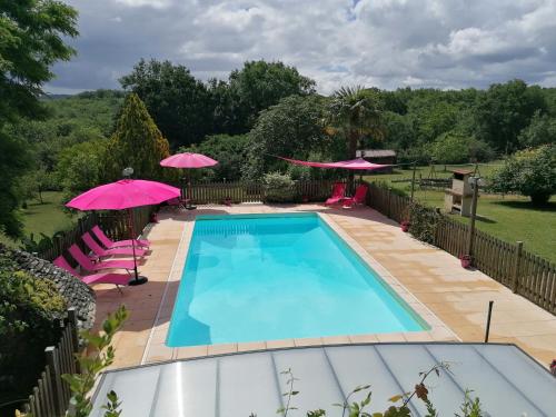 une piscine avec deux parasols roses à côté dans l'établissement Les gîtes d'Auriac, à Calès