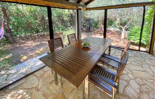 a wooden table and chairs on a screened in porch at 1 Bedroom Lovely Apartment In Nerezine in Nerezine