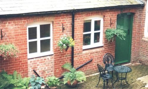 a brick house with a table and chairs and plants at The Butler's Pantry in Bungay