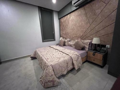 a bedroom with a bed and a night stand with a lamp at Ridge Apartments in Kano
