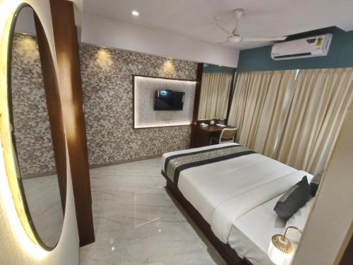 a bedroom with a large bed and a mirror at Hotel Manthan Stays - Airoli in Navi Mumbai