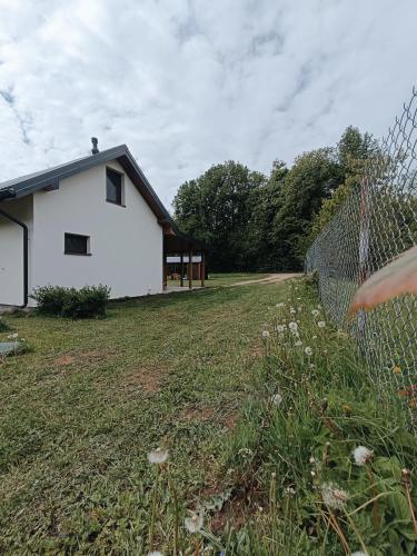 a white house with a fence next to a yard at Dom wśród łąk in Suwałki