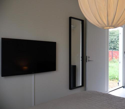 a flat screen tv on a wall next to a mirror at Cozy container Skillinge, Österlen in Skillinge