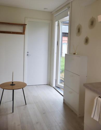 a white kitchen with a table and a door at Cozy container Skillinge, Österlen in Skillinge
