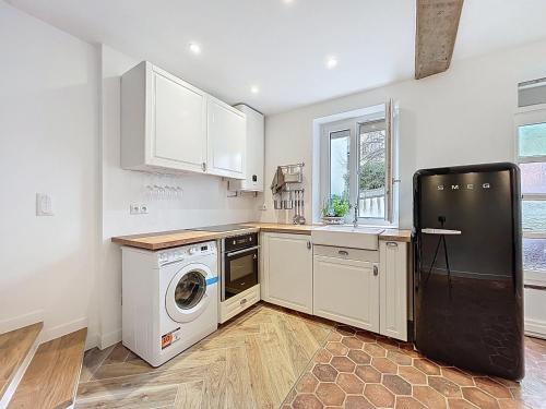 une cuisine avec des armoires blanches et une laveuse et une sécheuse dans l'établissement Jolie maison Trouville sur Mer, à Trouville-sur-Mer