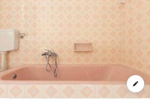 een roze badkuip in een badkamer met roze behang bij Villa Frida in Campomarino