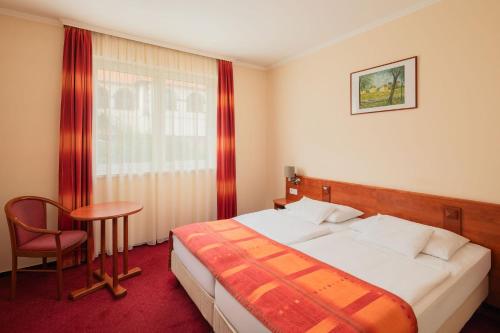a bedroom with a bed and a chair and a table at Erzsébet Park Hotel in Parád