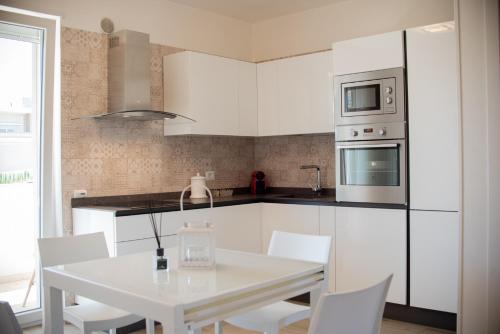 una cucina con mobili bianchi, tavolo e sedie bianchi di Sogno di mare a Monopoli