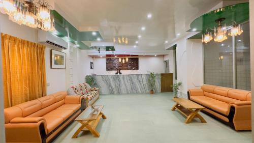 ダッカにあるHotel Dhaka City Innのオレンジ色の革張りのソファとテーブルのある待合室