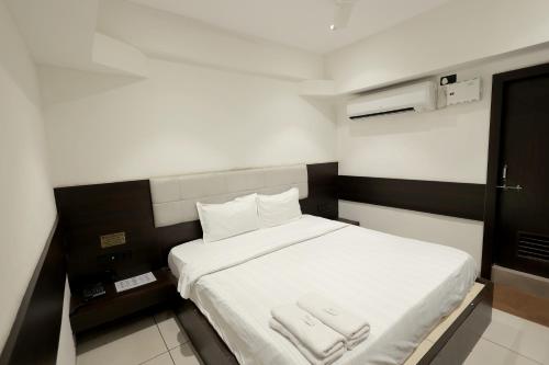a small room with a bed with two towels on it at Hotel Shagun, Piplod City Centre Surat in Surat
