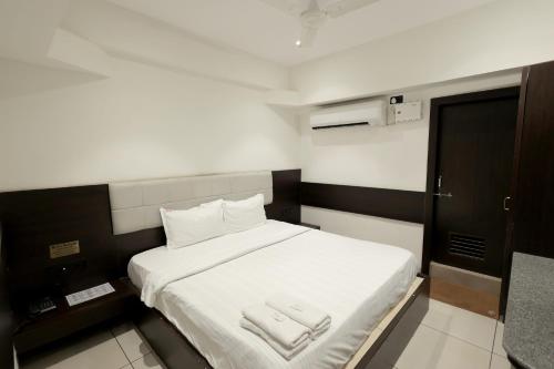 a bedroom with a bed with two towels on it at Hotel Shagun, Piplod City Centre Surat in Surat