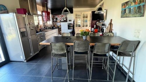 une cuisine avec une table avec des chaises et un réfrigérateur dans l'établissement Maison atypique familiale, à Étaules
