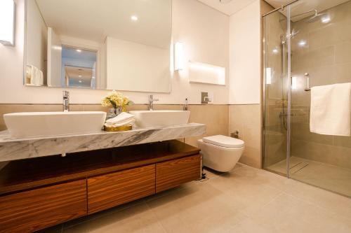 a bathroom with two sinks and a toilet and a shower at Peaceful 2BR Retreat Near Burj Al Arab in Dubai
