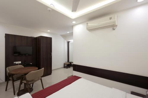a bedroom with a bed and a desk and a table at Hotel Shagun, Piplod City Centre Surat in Surat