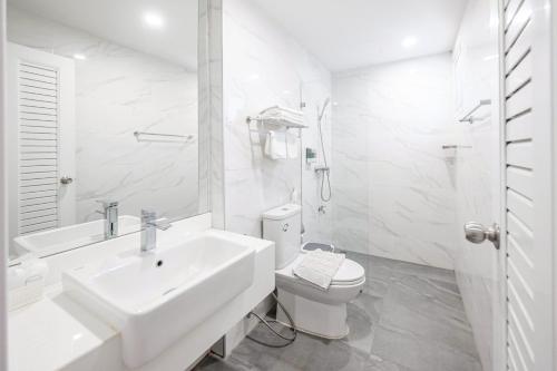 a white bathroom with a sink and a toilet at GRAND PA Hotel&Resort Lamphun Chiang Mai in Lamphun