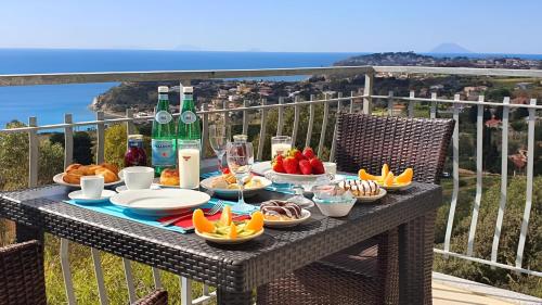 a table with fruit and wine bottles on a balcony at Agriturismo Le Ville con Piscina idromassaggio, Capo Vaticano in Ricadi