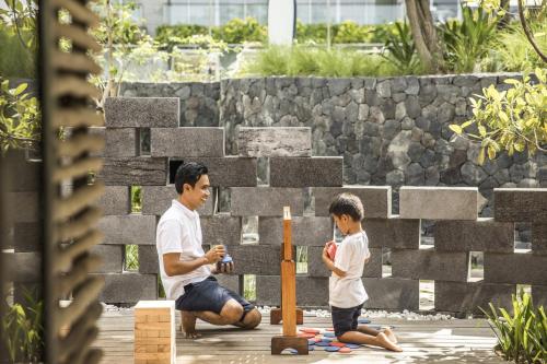 a man and a boy playing with a wooden bat at COMO Uma Canggu in Canggu