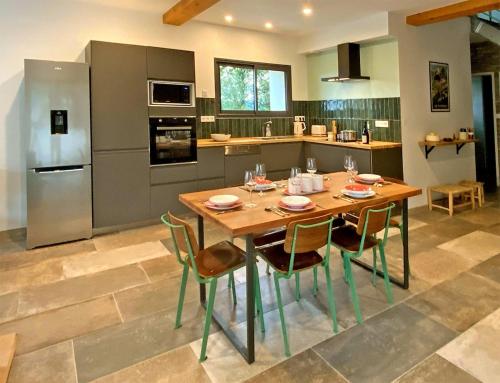 a kitchen with a wooden table and chairs in it at Grange Bernata, havre de paix sur la colline in Pontacq