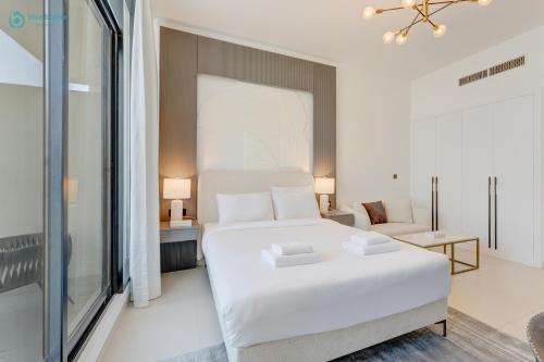 a white bedroom with a large bed and a chair at Bright & Luxury Studio with Balcony in Al Furjan in Dubai
