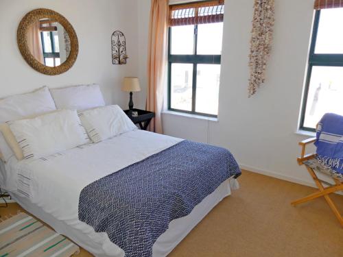 a bedroom with a bed and a chair and windows at Happy Wife in St. Helena Bay