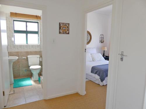 a bedroom with a bed and a bathroom with a toilet at Happy Wife in St. Helena Bay