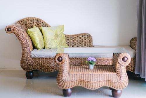a wicker chair with a table in a room at Wilacha Chiang Rai in Chiang Rai
