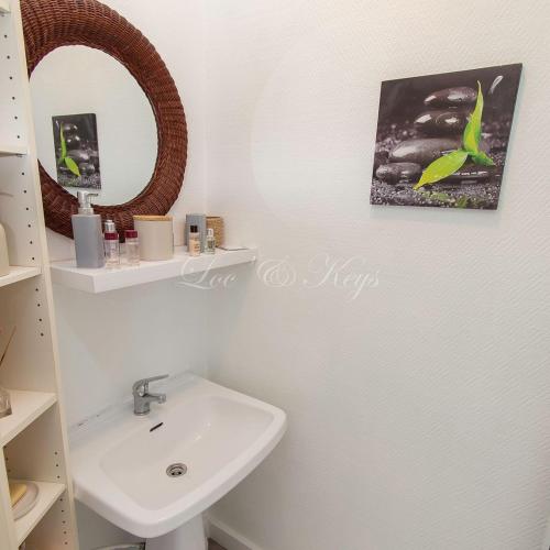 une salle de bain avec un lavabo et un miroir dans l'établissement Maison du Soleil Atypique, à Biscarrosse