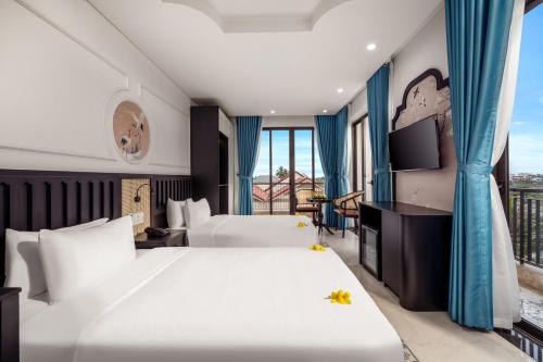 a hotel room with a large bed and a balcony at ELC Boutique Hoi An Hotel in Hoi An