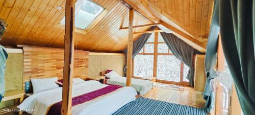 deux lits dans une chambre avec plafonds en bois dans l'établissement Shantchit Wellness Resort Hotel in Kasol Valley, à Kasol