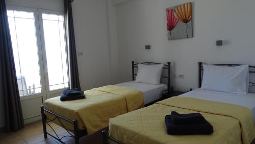 two beds in a room with windows at Hermes-Ios Rooms To Let in Ios Chora