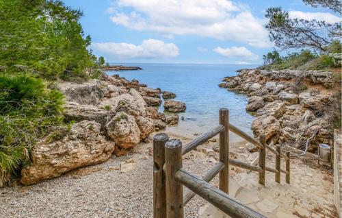 a wooden fence on a rocky beach near the ocean at Stunning Home In L'ametlla De Mar in L'Ametlla de Mar