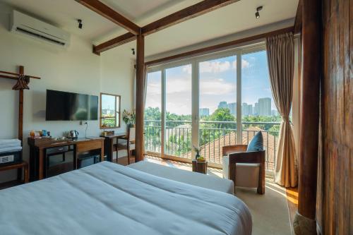 a bedroom with a bed and a desk and a large window at Nexus House Lang Bao Chi in Ho Chi Minh City