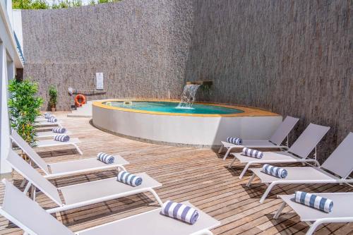 a patio with chairs and a swimming pool with a fountain at Villa Doris Suites in Lagos