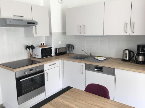 une cuisine blanche avec des armoires blanches et un évier dans l'établissement appartement proche de la plage , wimereux , 2 chambres , box stationnement , wifi, à Wimereux