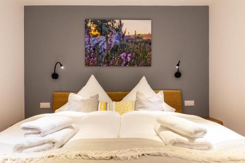 a bedroom with a white bed with a painting on the wall at Heide Ferien - Hof Bockelmann in Bispingen