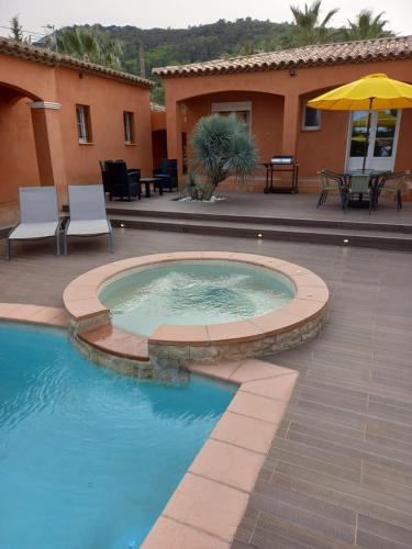 - une piscine avec un parasol et une maison dans l'établissement Villa La Lauzade, au Luc