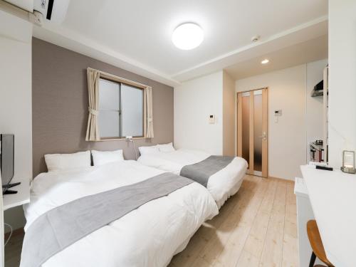 two beds in a white bedroom with a window at Ikebukuro 10min walk, Shinjuku 10min, Switch, Free Wi-Fi ,PocketWi-Fi in Tokyo