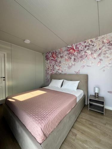 a bedroom with a bed with pink flowers on the wall at Le Jardin Glamping in Oraviţa