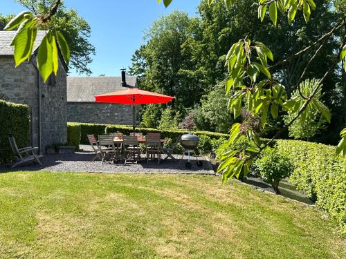 a patio with a table and chairs and an umbrella at Les Gîtes du Château de Bellaire in Gesves