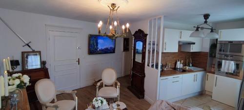 une cuisine avec des placards et des chaises blancs et un lustre dans l'établissement L'escapade Royale, à Moret-sur-Loing