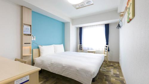a bedroom with a white bed and a large window at Toyoko Inn Satsuma Sendai eki Higashi guchi in Satsumasendai