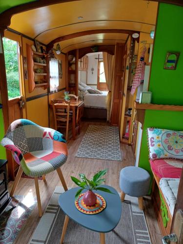 un salon avec un bus avec une table dans l'établissement Roulotte Mon rêve en Normandie, à Le Mesnil-Garnier