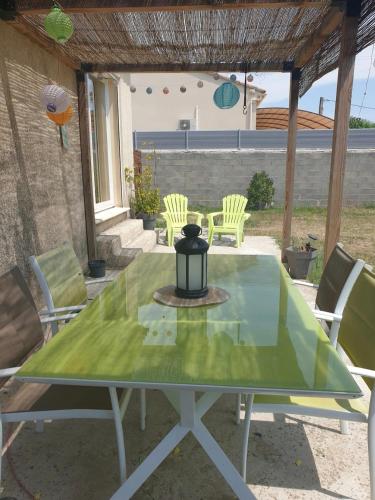une table verte avec des chaises sur la terrasse dans l'établissement Maison en campagne, à Monteux