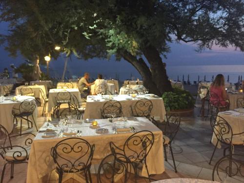 a restaurant with tables and chairs with a view of the ocean at Hotel Poseidon in Diamante