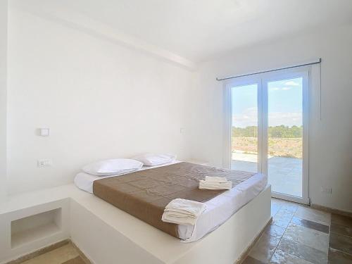 a white bedroom with a bed and a large window at Residenza del Duca in Martina Franca