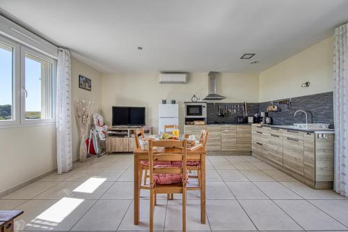 eine Küche mit einem Tisch und Stühlen darin in der Unterkunft Au cœur des vignes in Montagne