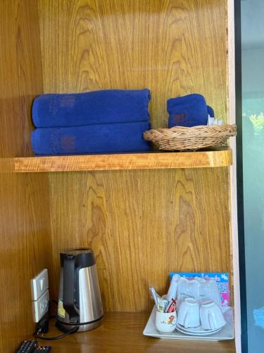 a shelf with a coffee maker and blue towels at Baan Suan Nam Resort in Don Sak