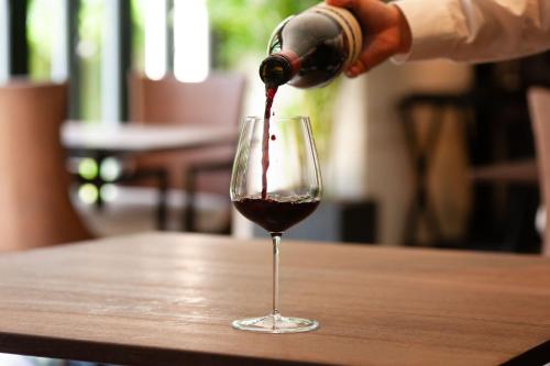 a person pouring red wine into a wine glass at UMITO Okinawa Onnason in Onna